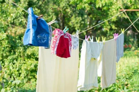 Clean laundry drying on line outside green background Stock Photos