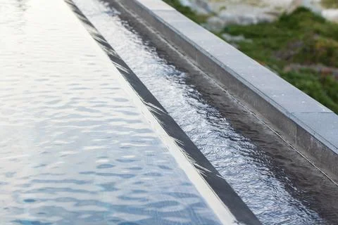 A clean, linear pool edge features a calm, reflective water surface Stock Photos
