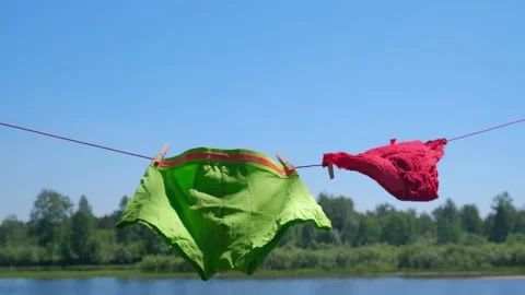 Clean linen is drying on rope, swinging in the wind. bright underwear of couple. Stock Footage 199452657