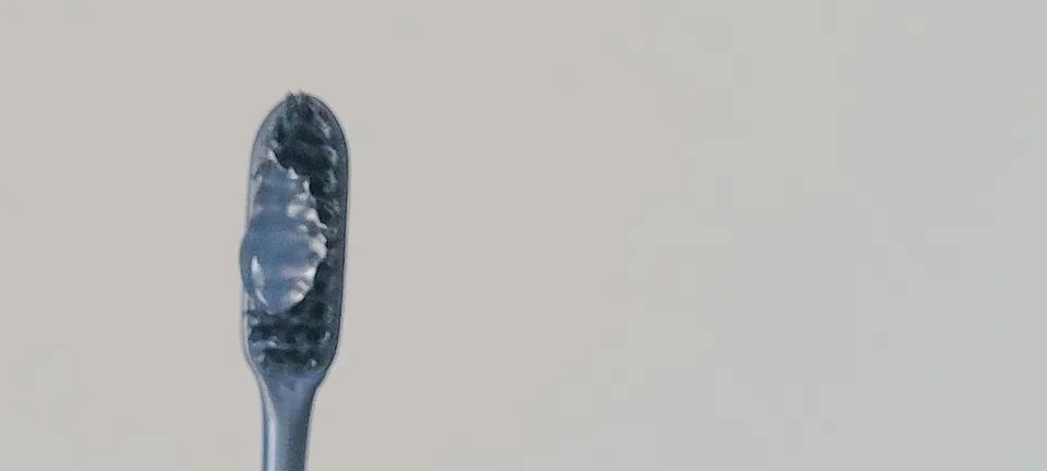 Clean macro image of toothpaste resting on toothbrush bristles. Minimal den.. Fotos Stock