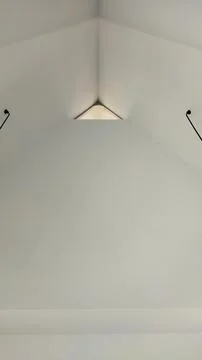 A clean minimalist ceiling featuring a triangular skylight and two hanging li Stock Photos