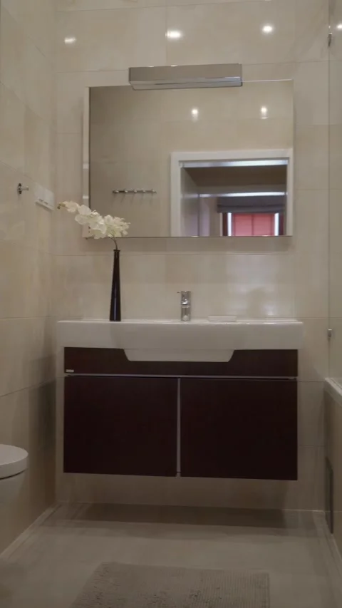 Clean Modern Bathroom Featuring Light Tiles, Dark Vanity and Bath Shower Stock Footage 309297153