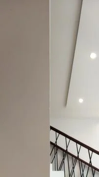 A clean modern interior ceiling with recessed lights and a staircase railing  Stock Photos