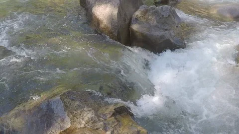 Clean mountain water runs down small mountain river over rocks and boulders Stock Footage 99671029