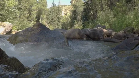 Clean mountain water runs down small mountain river over rocks and boulders Stock Footage 99674333