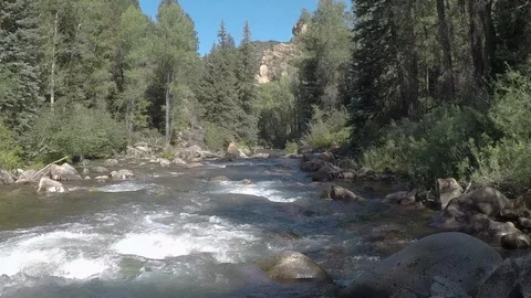 Clean mountain water runs down small mountain river over rocks and boulders Stock Footage 99677093