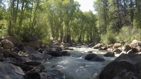 Clean mountain water runs down small mountain river over rocks and boulders 動画素材 99678387