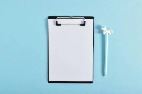 A clean notebook with a blue pen on a light blue background, a place for text Stock-Fotos