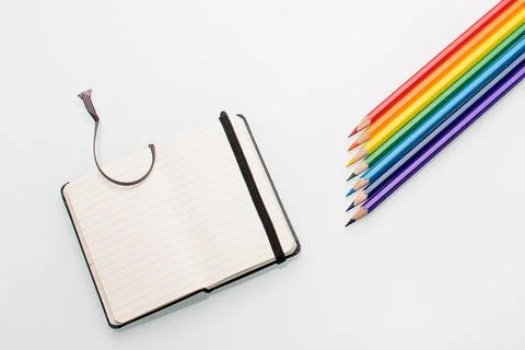 Clean notepad and rainbow color pencils in the shape of an arrow on a white Stock Photos