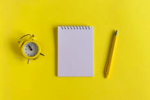 Clean Notepad, clock and pen on a yellow background, spiral notebook on the t Foto stock