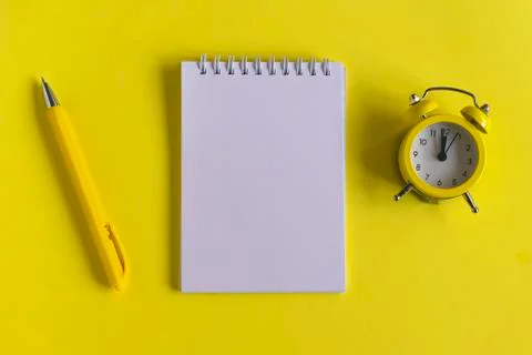 Clean Notepad, clock and pen on a yellow background, spiral notebook on the t Foto stock