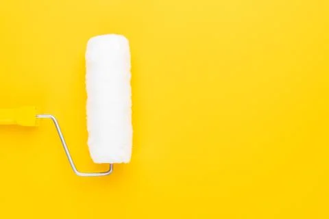 Clean paint roller with yellow handle on the yellow background with copy space Stock Photos