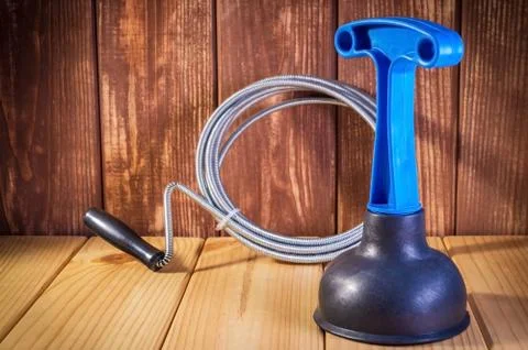 Clean plastic plunger with blue handle and cable on wooden background Stock Photos