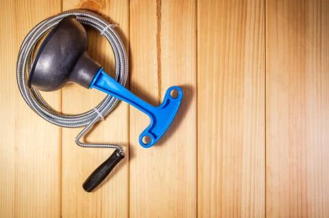 Clean plastic plunger with blue handle and cable on wooden background Stock Photos
