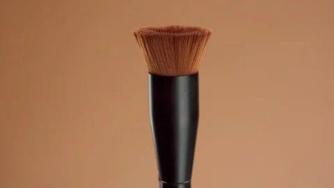 A clean round foundation brush with a liquid foundation for deep skin tones Stock Footage 128630390