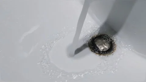 Clean running water flowing down the drain of a white ceramic bathroom sink. Vídeos de archivo 344091754