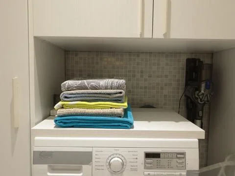 Clean set terry bath towels stacked on top of each other on washing machine in Stock Photos