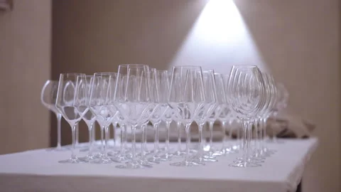 Clean transparent glasses of different shapes on table with white tablecloth in Stock Footage 344757006