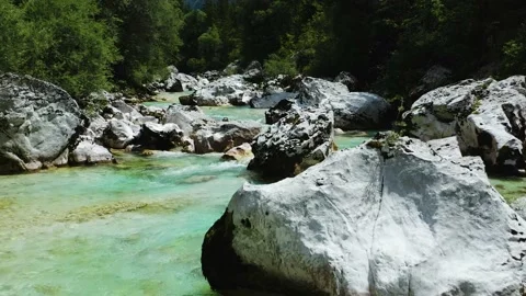 Clean turquoise/Emerald Soca River Flows Between Big Rocks With Forest in Back Stock Footage 142967964