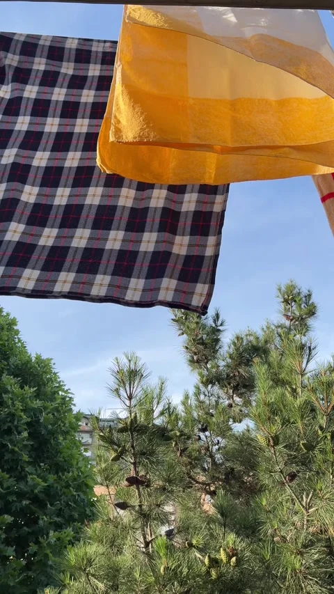 Clean washed clothes. Checkered yellow blanket is being dried on rope in street Stock Footage 278118950