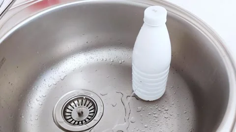 Clean Water Flow Over Bottle in Stainless Steel Sink Close-Up Video stock 318579056