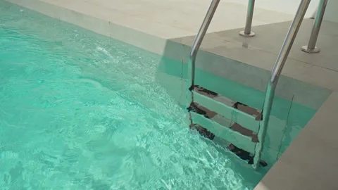 Clean water gently ripples around the steps of a metal ladder in a turquoise Stock Footage 320806325