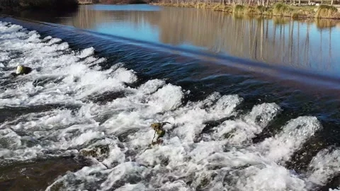 The clean water river flows through a small waterfall on a sunny day Stock Footage 169256951