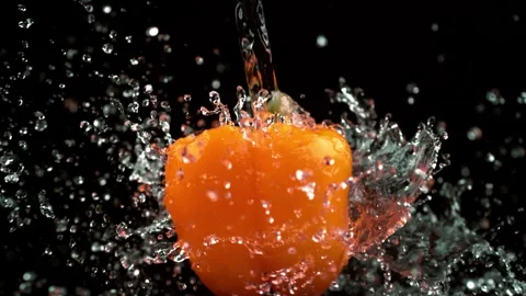Clean water stream falling on fresh orange bell pepper slow motion Stock Footage 327573675