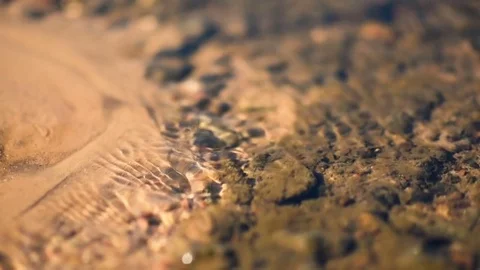 Clean water stream flows through the sand and glare in the sun Stock Footage