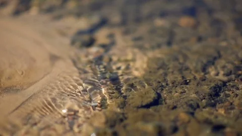 Clean water stream flows through the sand and glare in the sun Video stock 78929564