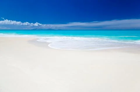 A clean white caribbean beach with deep blue sky and turquoise water. The isl Stock Photos