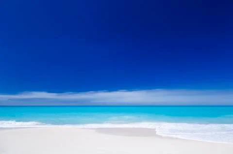 A clean white caribbean beach with deep blue sky and turquoise water. Stock Photos