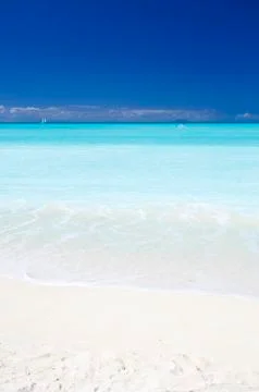 A clean white caribbean beach with deep blue sky and turquoise water. The isl Stock Photos