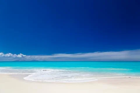 A clean white caribbean beach with deep blue sky and turquoise water. The isl Stock Photos