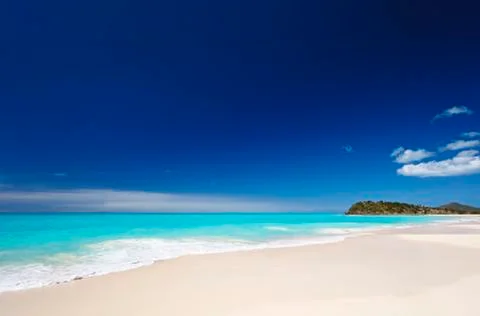A clean white caribbean beach with deep blue sky and turquoise water. Stock Photos