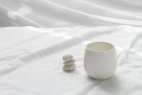 Clean white ceramic tea drinking cup and pebble rock in wellness zen Japanese Stock Photos