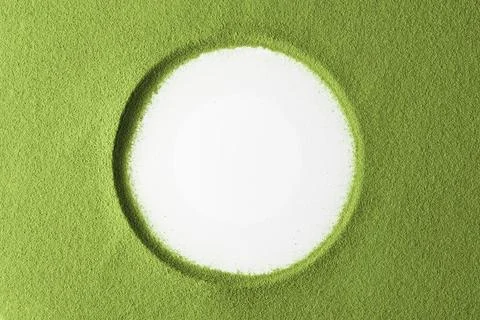 A clean white circle sits in vibrant matcha powder and suggests natural Stock Photos