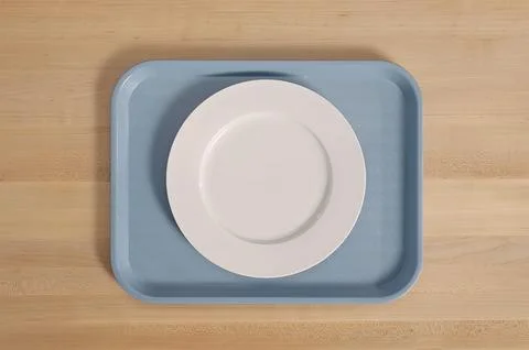 Clean white dinner plate centered on rectangular blue cafeteria tray restin.. Stock Photos