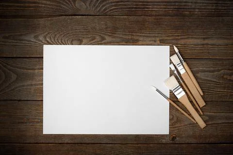 A clean white sheet and brushes on a wood textured background with space to c Stock Photos