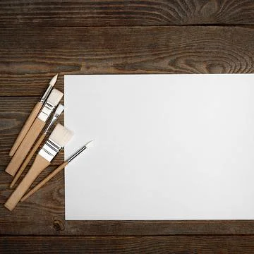 A clean white sheet and brushes on a wood textured background with space to c Stock Photos