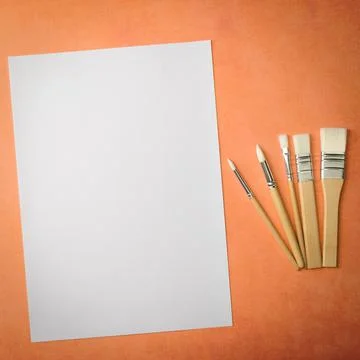 A clean white sheet and brushes on a textured background with space to copy. Stock Photos