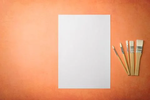 A clean white sheet and brushes on a textured background with space to copy. Stock Photos