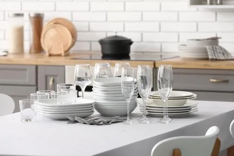 Clean white table setting with stacked plates, bowls, glasses, and silverware Stock Photos