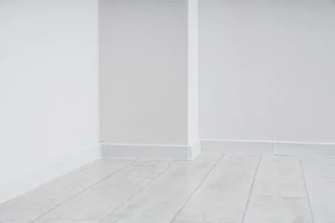 Clean white wall corner with baseboard and light wood laminate flooring for i Stock Photos