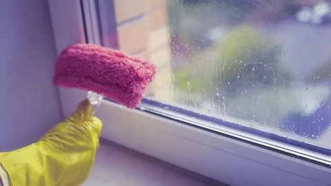 Clean the window with a scraper in a yellow rubber glove. SLOW MOTION. HD Stock Footage 77575644