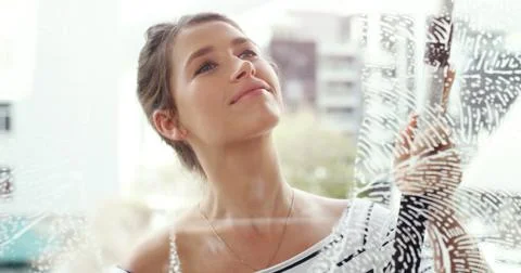 Clean windows fixes everything. a young woman cleaning her windows at home. Stock Photos