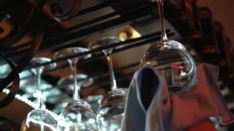 Clean wine glasses prepared by bartender and hung on the bar at a restaurant Stock Footage 90639283