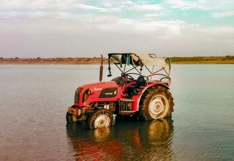 Cleaned Tractor standing in Water, Reflection seen in river water. 스톡 사진