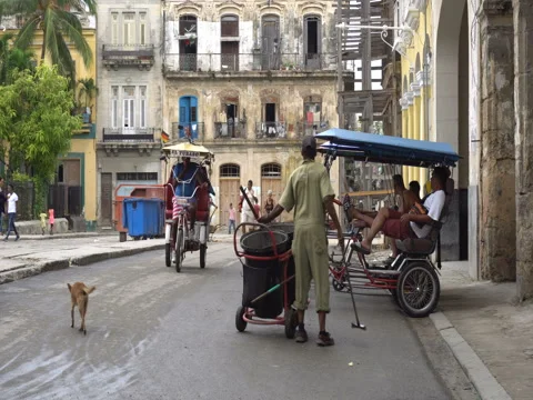 Cleaner of garbage cleans dirty streets.  Trishaws without passengers are parked Stock Footage 70857525