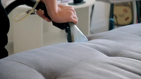 Cleaner hands using vacuum cleaner to meticulously clean sofa from stains dust. Stock Footage 311799296
